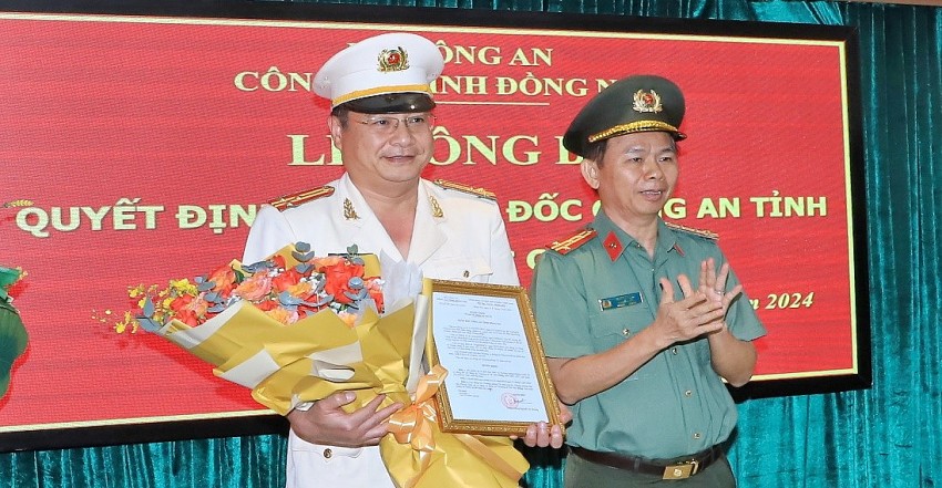 Đại tá Trần Tiến Đạt, Phó Giám đốc Công an tỉnh trao quyết định và tặng hoa chúc mừng Thượng tá Vũ Văn Dũng.
