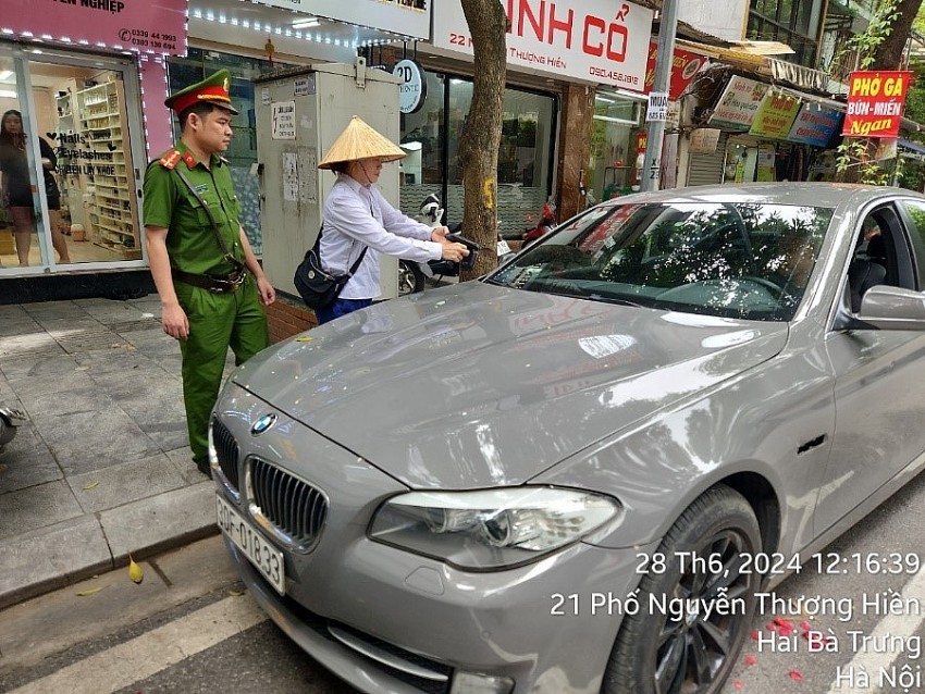 Cán bộ Phòng Cảnh sát QLHC về TTXH phối hợp cùng nhân viên Công ty khai thác điểm đỗ Hà Nội vận hành thiết bị kiểm soát phương tiện vào bãi gửi xe.