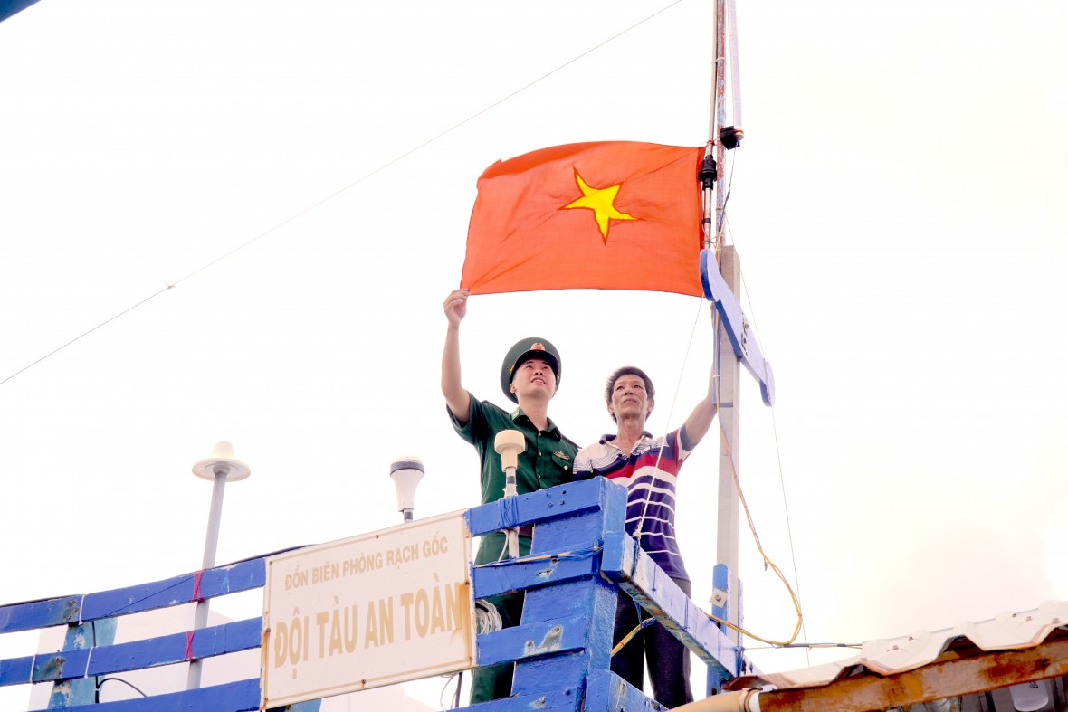 Biên phòng hỗ trợ ngư dân treo cờ trên tàu thuộc Đội tàu thuyền an toàn