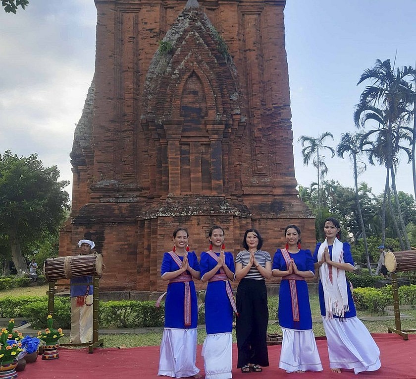 Du khách chụp ảnh lưu niệm với những cô gái Chăm bên tháp cổ ở Bình Định. (Ảnh: Phan Hiếu)