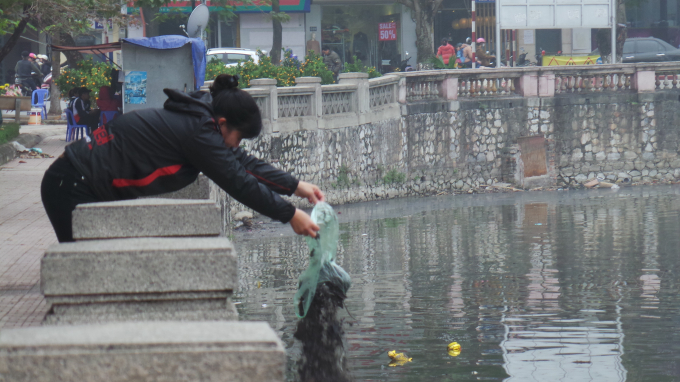 Một người d&acirc;n đang đổ tro xuống hồ Thủ Lệ