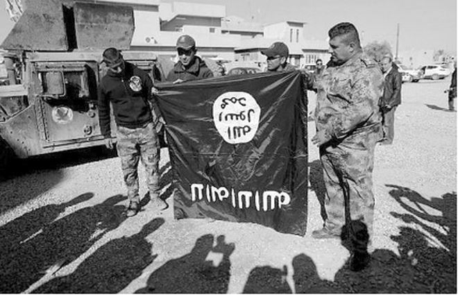 Qu&acirc;n đội Iraq cầm l&aacute; cờ nh&oacute;m IS ở ngoại &ocirc; Mosul.