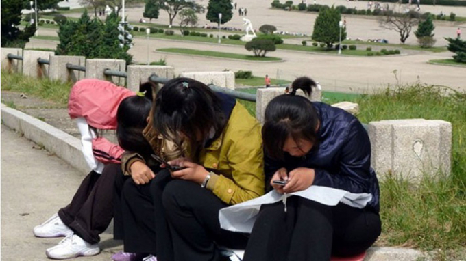 C&aacute;c c&ocirc; g&aacute;i trẻ ở Triều Ti&ecirc;n sử dụng điện thoại di động tại c&ocirc;ng vi&ecirc;n - Ảnh: AFP.