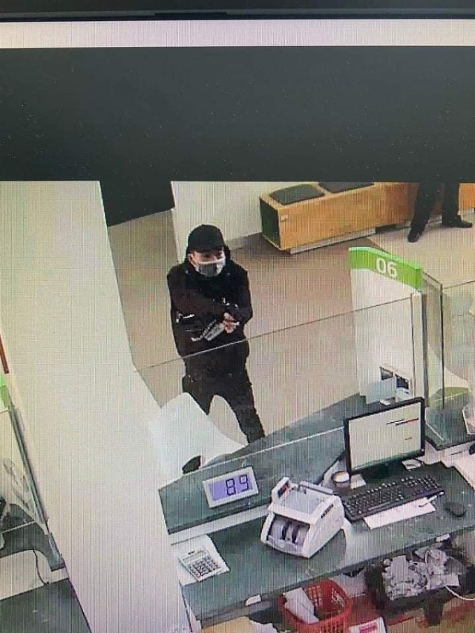 Tên cướp dùng súng uy hiếp nhân viên ngân hàng.