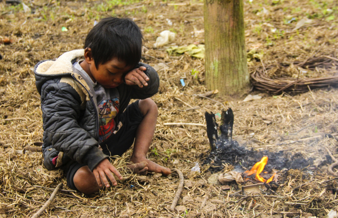 Một đứa trẻ ở bản K-Ai tự đốt lửa để xua đi c&aacute;i lạnh. (Ảnh: Hải Long).