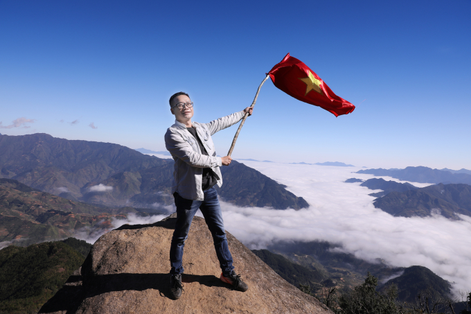 Tác giả với Quốc kỳ ở độ cao gần 3000 m so với mực nước biển của đỉnh Tà Xùa ở Trạm Tấu, Yên Bái.