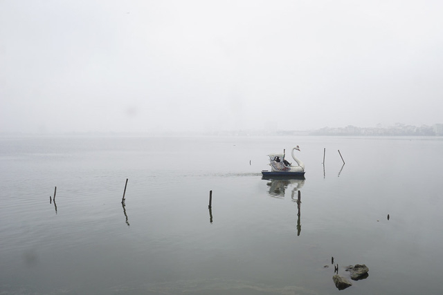 Mặt nước Hồ T&acirc;y phẳng lặng trong kh&ocirc;ng gian lờ mờ sương m&ugrave; d&agrave;y đặc.