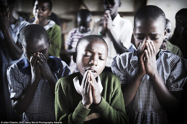 Tại một ng&ocirc;i trường ở miền qu&ecirc; Uganda, Đ&ocirc;ng Phi, trẻ em cầu nguyện đầu giờ s&aacute;ng trước khi lớp học bắt đầu.