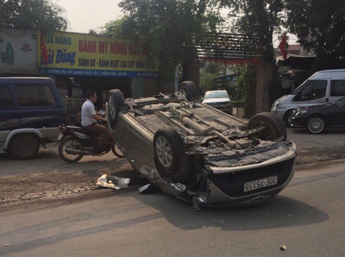 Sau khi g&acirc;y tai nạn, chiếc xe &ocirc;t&ocirc; m&agrave;u ghi bị lật ngửa giữa đường.