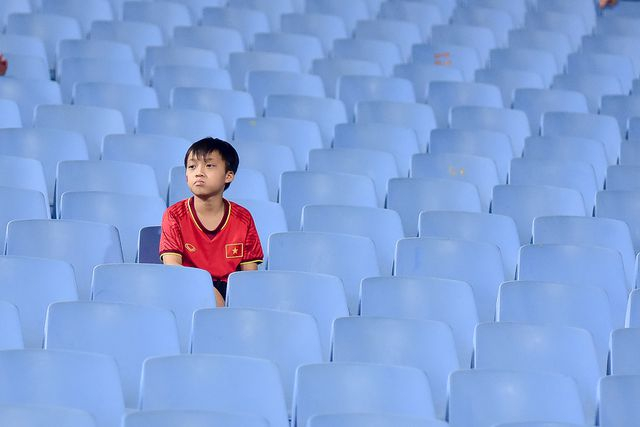 Một em nhỏ ngồi giữa những chiếc ghế trống để cổ vũ đội tuyển U23 Việt Nam thi đấu với đội tuyển Brunei.