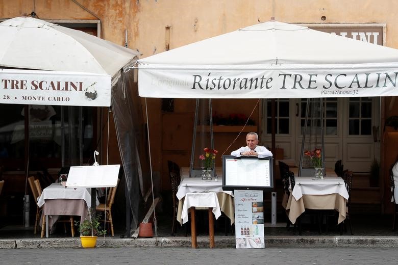 Một người đàn ông đứng đằng sau quầy thực đơn tại một nhà hàng trống ở quảng trường Piazza Navona ở Rome, ngày 5 tháng 3.
