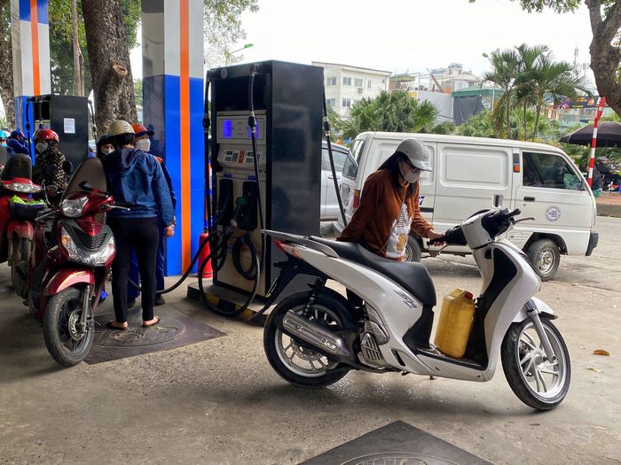 Nhiều người mang can, chai nhựa đi mua xăng trước giờ tăng giá. Ảnh: Hồng Quang.