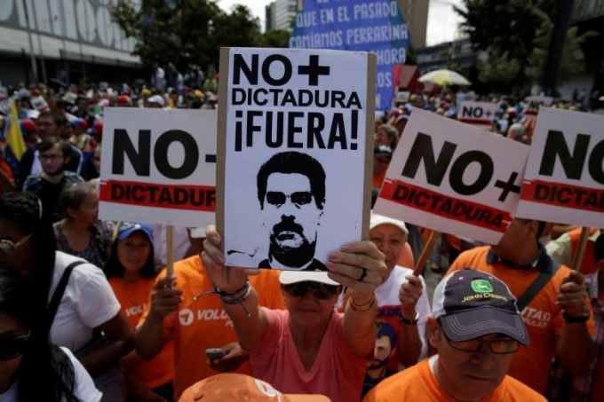 Một người ủng hộ phe đối lập cầm bảng với h&igrave;nh ảnh Tổng thống Nicolas Maduro v&agrave; d&ograve;ng chữ: &ldquo;Kh&ocirc;ng c&oacute; chỗ cho chế độ độc t&agrave;i&rdquo;.