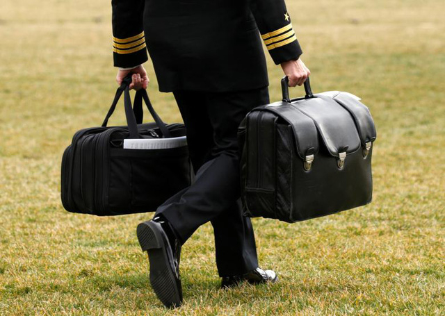 Một sĩ quan qu&acirc;n sự mang vali chứa m&atilde; hạt nh&acirc;n theo sau Tổng thống Trump khi &ocirc;ng chuẩn bị bước l&ecirc;n chuy&ecirc;n cơ Marine One.