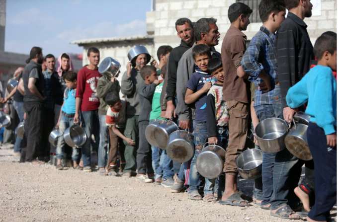 Người d&acirc;n Syria đứng xếp h&agrave;ng để nhận thức ăn được viện trợ. Ảnh: Reuters.