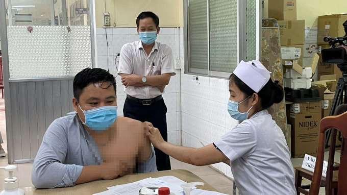 Trong hình là Bác sĩ Bạch Thái Bình - Giám đốc Trung tâm kiểm soát bệnh tật Đồng Nai (áo trắng đứng sau) trực tiếp giám sát mũi tiêm đầu tiên trong ngày đầu triển khai tiêm chủng tại Đồng Nai.