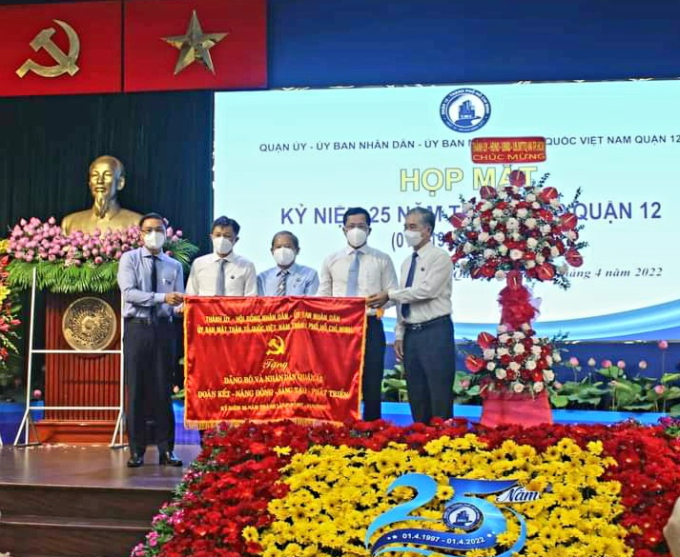 Phó chủ tịch UBND TP.HCM - Ngô Minh Châu (ngoài cùng bên phải) trao cờ của Thành ủy - HĐND - UBND - Ủy ban MTTQ Việt Nam TP.HCM cho lãnh đạo Q.12. Ảnh: Đình Chiến