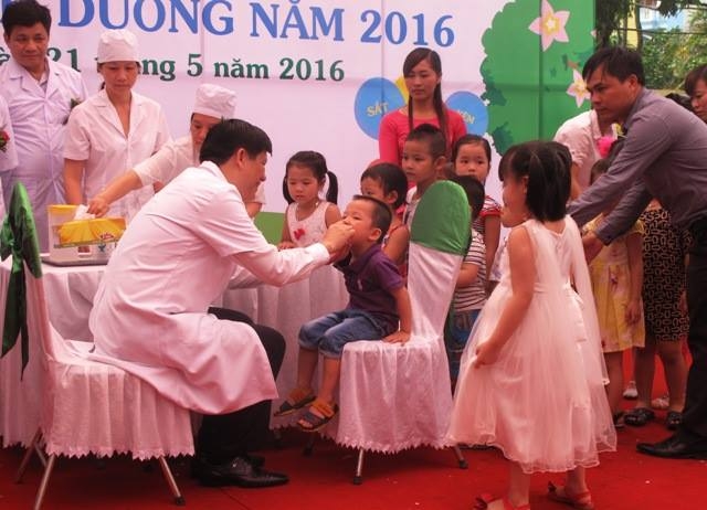 Thứ trưởng Bộ Y tế Nguyễn Thanh Long cho trẻ nhỏ uống thuốc bổ sung vi chất.