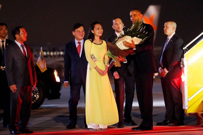 Tổng thống Mỹ đ&aacute;p m&aacute;y bay xuống s&acirc;n bay Nội B&agrave;i (H&agrave; Nội) tối 22/5. &Ocirc;ng được một nữ sinh vi&ecirc;n đại diện Việt Nam tặng hoa ch&agrave;o đ&oacute;n.