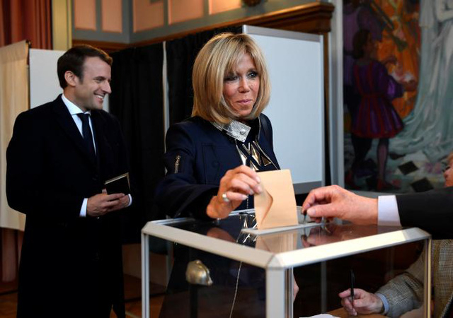 Reuters cho biết, sau khi &ocirc;ng Macron trở th&agrave;nh tổng thống, b&agrave; Brigitte Trogneux c&oacute; thể sẽ đ&oacute;ng vai tr&ograve; l&agrave; cố vấn quan trọng của chồng. Trong ảnh: Vợ chồng &ocirc;ng Macron tại một điểm bỏ phiếu ng&agrave;y 7/5. (Ảnh: Reuters)