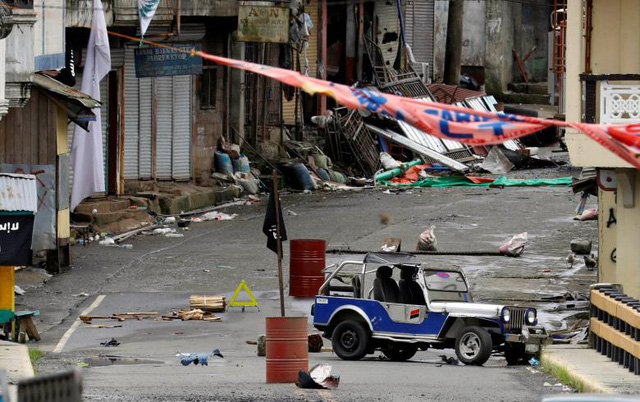 Sau một tuần kể từ ng&agrave;y Maute, nh&oacute;m phiến qu&acirc;n từng thề trung th&agrave;nh với IS, tấn c&ocirc;ng th&agrave;nh phố Marawi tr&ecirc;n đảo Mindanao miền nam Philippines h&ocirc;m 23/5, qu&acirc;n đội ch&iacute;nh phủ tuy&ecirc;n bố đ&atilde; gi&agrave;nh quyền kiểm so&aacute;t th&agrave;nh phố n&agrave;y. Tuy nhi&ecirc;n, vẫn c&ograve;n một số khu vực nhất định đang bị phiến qu&acirc;n Maute chiếm đ&oacute;ng buộc qu&acirc;n đội ch&iacute;nh phủ phải dốc to&agrave;n lực để &ldquo;dẹp loạn&rdquo;. Trong ảnh: Một khu vực tại Marawi bị nh&oacute;m Maute chiếm giữ với cờ IS (m&agrave;u đen) được cắm ngay giữa đường đi.