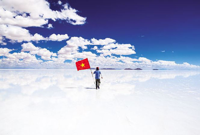 Anh Nguyễn Ho&agrave;ng Bảo cầm cờ Tổ quốc tại c&aacute;nh đồng muối Uyuni de Salar ở Bolivia. Ảnh: NVCC.