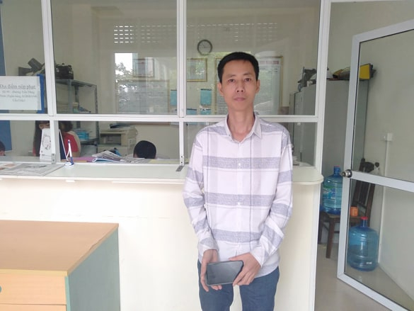 Lái xe taxi Nguyễn Xuân Cường đến trụ sở Đội thanh tra GTVT Hà Nội giao trả chiếc điện thoại, để đơn vị trả lại cho du khách bỏ quên.