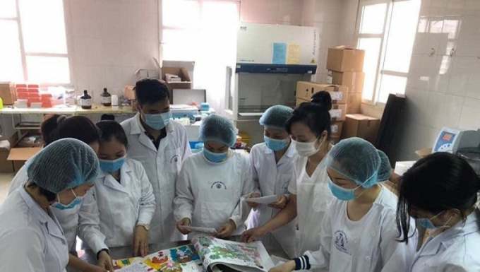 Cán bộ Trung tâm kiểm soát Bệnh tật (CDC) Hà Nội xem tranh do các em học sinh Trường tiểu học Chu văn An (Hà Nội) tặng.
