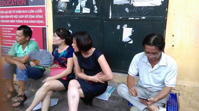 Phụ huynh ngồi chờ con trước điểm thi trường THPT Việt Đức vớ&iacute; t&acirc;m trạng hồi hộp, lo lắng. (ảnh: Thu Hường)