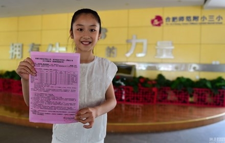 Học sinh tiểu học Huang Sihan cầm tr&ecirc;n tay giấy tuyển thẳng của trường Đại học nghệ thuật An Huy.