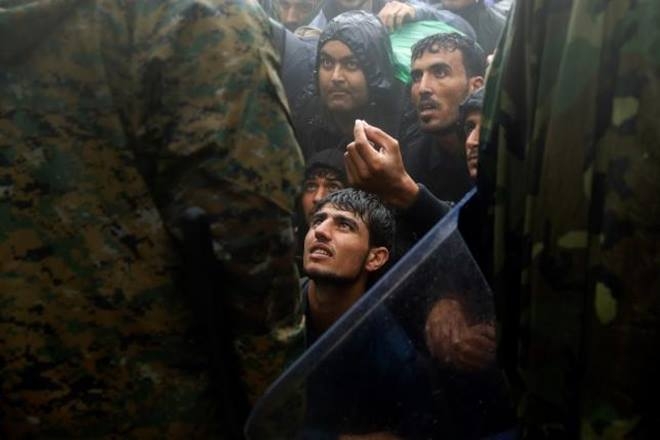 Những người tị nạn xin cảnh s&aacute;t&nbsp;cho ph&eacute;p vượt qua bi&ecirc;n giới từ Hy Lạp v&agrave;o Macedonia trong một cơn mưa. (Ảnh: Reuters)