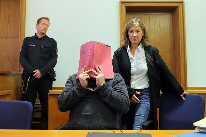 Niels Hoegel che mặt trước ống kính báo chí trong một phiên xử.