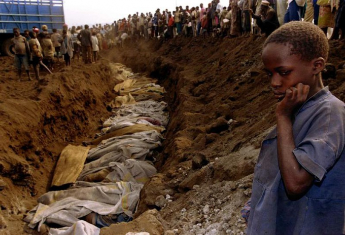 Một cô bé tị nạn người Rwanda đứng nhìn những thi thể trong một ngôi mộ tập thể ngày 20/7/1994.