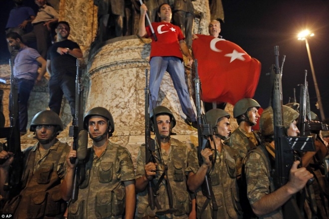 Binh sĩ đứng g&aacute;c ở quảng trường Taksim tại Istanbul, trong l&uacute;c những người ủng hộ Tổng thống Erdogan mang theo quốc kỳ phản đối đảo ch&iacute;nh. Ảnh:&nbsp;AP