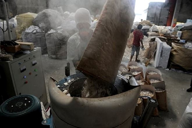 Công nhân trút bỏ xốp vụn vào máy nghiền trong cơ sở tái chế ở thành phố Valenzuela, phía bắc Manila.