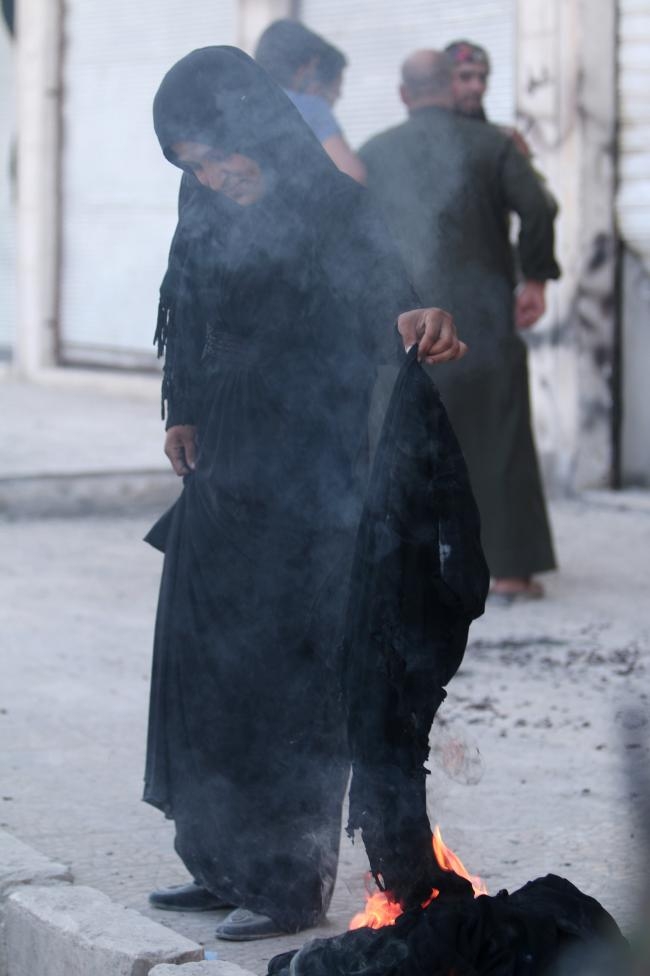Nhiều phụ nữ đốt khăn che mặt sau khi IS bị đẩy l&ugrave;i ra khỏi th&agrave;nh phố. (Ảnh: Reuters)