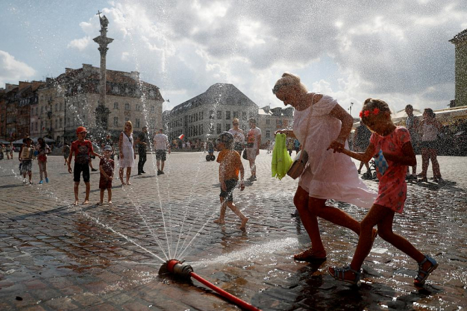 Kh&ocirc;ng ngại ướt, người d&acirc;n chơi đ&ugrave;a với v&ograve;i nước từ xe cứu hỏa khi nhiệt độ vượt mức 37 độ C tại Prague, Cộng h&ograve;a S&eacute;c. Ảnh: David W Cerny/Reuters