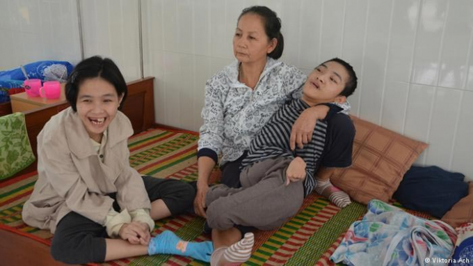 Người mẹ đang phải chăm s&oacute;c hai đứa con bị di chứng chất độc da cam. Ảnh: dw.com
