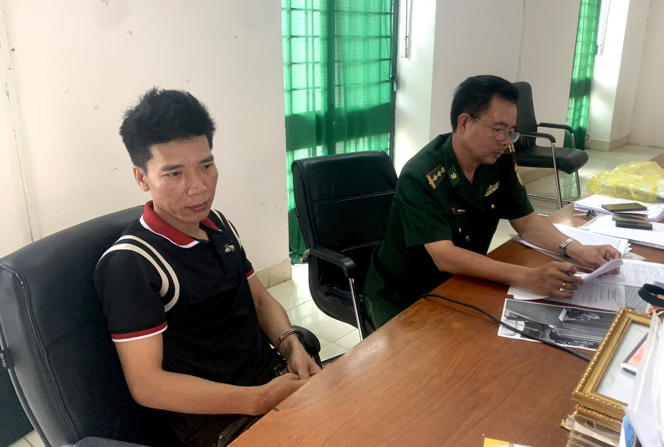 Cán bộ Đồn Biên phòng CKQT Mộc Bài lấy lời khai đối tượng Nguyễn Thành Trung (áo đen).