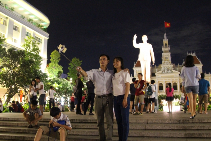 Hai vợ chồng ghi lại khoảng khắc hạnh ph&uacute;c b&ecirc;n tượng đ&agrave;i chủ tịch Hồ Ch&iacute; Minh v&agrave; quốc kỳ Việt Nam tại phố đi bộ Nguyễn Huệ