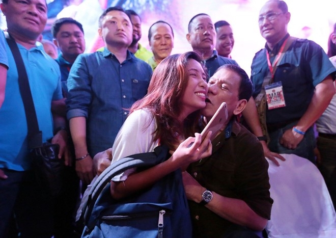 &Ocirc;ng Duterte h&ocirc;n m&aacute; một người phụ nữ trong buổi vận động tranh cử tổng thống. (Ảnh:Inquirer)