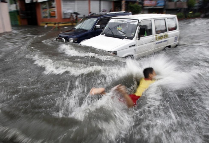 Một cậu b&eacute; bơi qua đoạn đường bị ngập khi b&atilde;o&nbsp;Muifa đổ bộ v&agrave;o Philippines năm 2011. (Ảnh: Reuters)