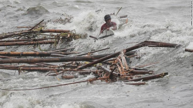 Cơ quan cứu trợ Philippines cảnh b&aacute;o, h&agrave;ng triệu người c&oacute; nguy cơ bị ngập lụt v&agrave; lở đất. 3 trường hợp thiệt mạng đầu ti&ecirc;n do b&atilde;o Mangkhut tại Philippines đ&atilde; được x&aacute;c nhận. Ảnh: Một người đ&agrave;n &ocirc;ng bị s&oacute;ng đ&aacute;nh khi đang cố thu nhặt một số vật liệu tr&ocirc;i ngo&agrave;i biển ở Manila.