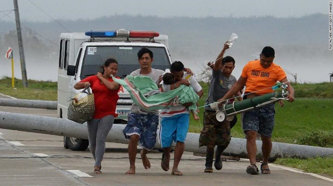 Một người cha đang cố chuyển đứa con đang bị ốm sang một chiếc xe kh&aacute;c sau khi chiếc xe cấp cứu kh&ocirc;ng thể di chuyển tiếp vị cột điện đổ chắn ngang đường ở thị trấn Baggao, bắc Manila.