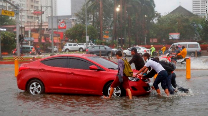 Một v&agrave;i người d&acirc;n đang gi&uacute;p đẩy chiếc xe &ocirc; t&ocirc; khỏi đoạn đường ngập nước ở Manila.