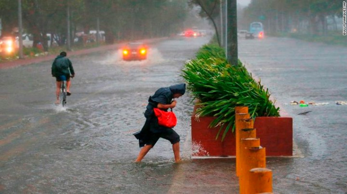 Một v&agrave;i người đi trong cơn mưa lớn v&agrave; gi&oacute; mạnh ở Manila.