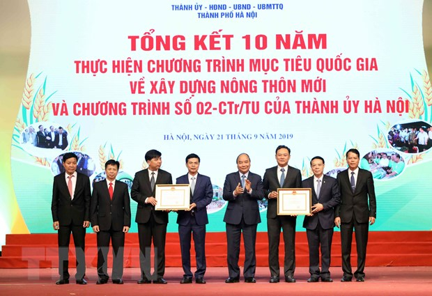 Thủ tướng Nguyễn Xuân Phúc trao bằng công nhận đạt chuẩn nông thôn mới năm 2019 cho huyện Quốc Oai và huyện Gia Lâm. (Ảnh: Văn Điệp/TTXVN)