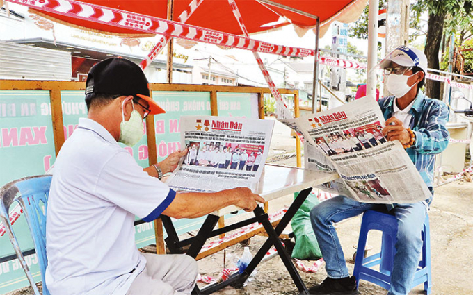 Người dân đọc báo Nhân Dân tại chốt bảo vệ “vùng xanh” ở tổ 4, khu phố 6, phường Tân Tiến, TP Biên Hòa (Đồng Nai).