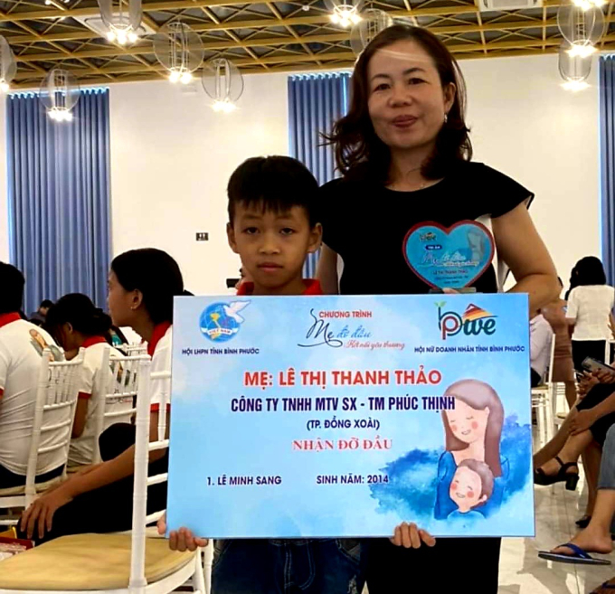 Đại diện Công ty TNHH XNK Hạt điều Phúc Thịnh Winut, bà Lê Thị Thanh Thảo nhận đỡ đầu cháu Lê Minh Sang, sinh năm 2014. Ảnh: Lê Thảo