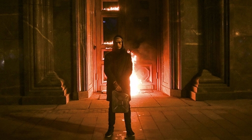 Pyotr Pavlensky tay cầm can xăng, đứng trước đống lửa tại cửa trụ sở FSB. &nbsp;(Ảnh: Reuters)